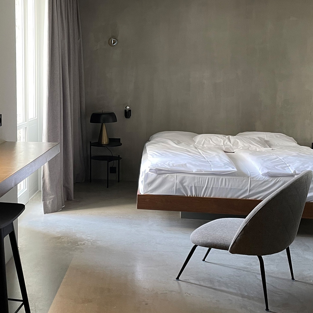 Zimmer mit großem Doppelbett in modernem Stil, links Regal/Ablage mit Beleuchtung