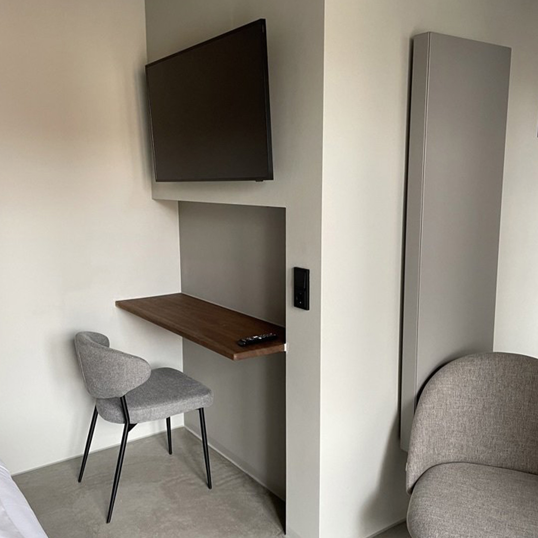 Zimmer mit Wand‑Smart‑TV über Schreibtisch, Stuhl davor – hell und funktional eingerichtetund Smart TV an der Wand im Walthers am Goetheplatz